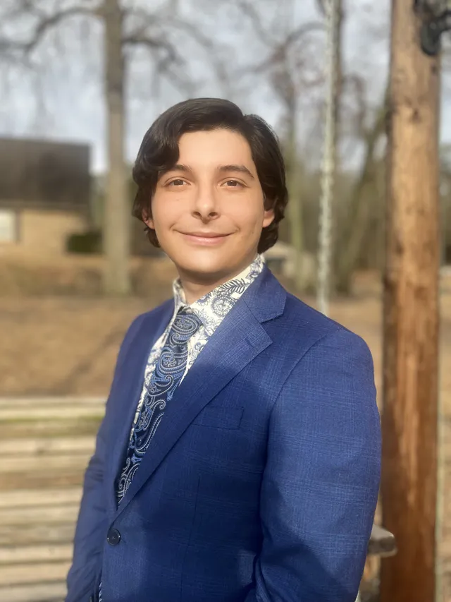 Jorge Naranjo Jr smiling in a navy suit and paisley tie